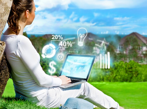 Young beautiful woman sitting under a tree and working with her